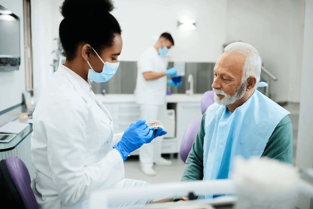 A dentist showing a patient an implant on a model